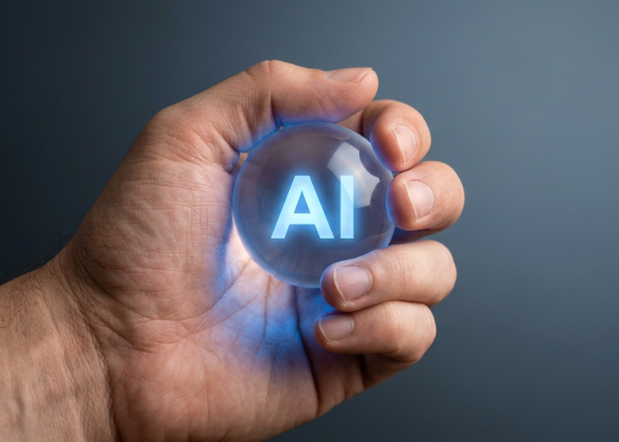 A hand holding a small glowing orb with the text “AI” inside on a clean background.